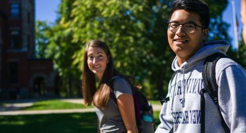三个学生在UNH校园里微笑着散步