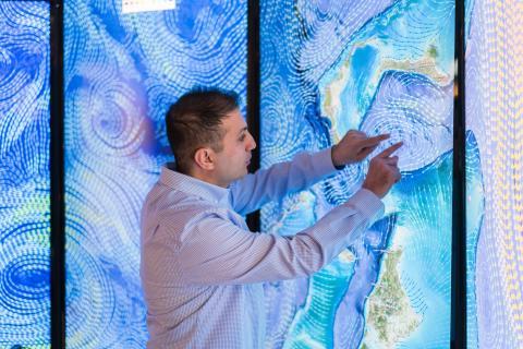 埃罗尔·艾加尔在达勒姆的海岸和海洋测绘中心进行数据可视化研究，他的硕士论文使用了一个巨大的彩色屏幕墙壁投影.